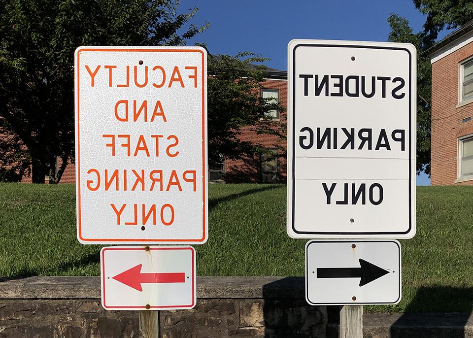 two signs; one says student parking left, other fauclty parking right