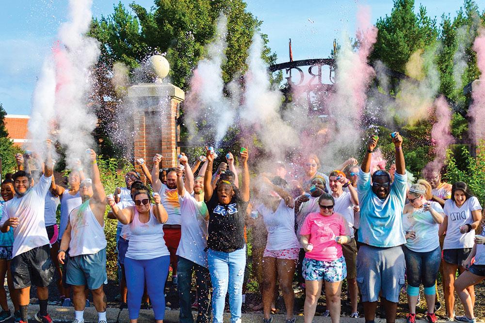一大群希腊生活学院的学生将各种颜色的灰尘抛向空中